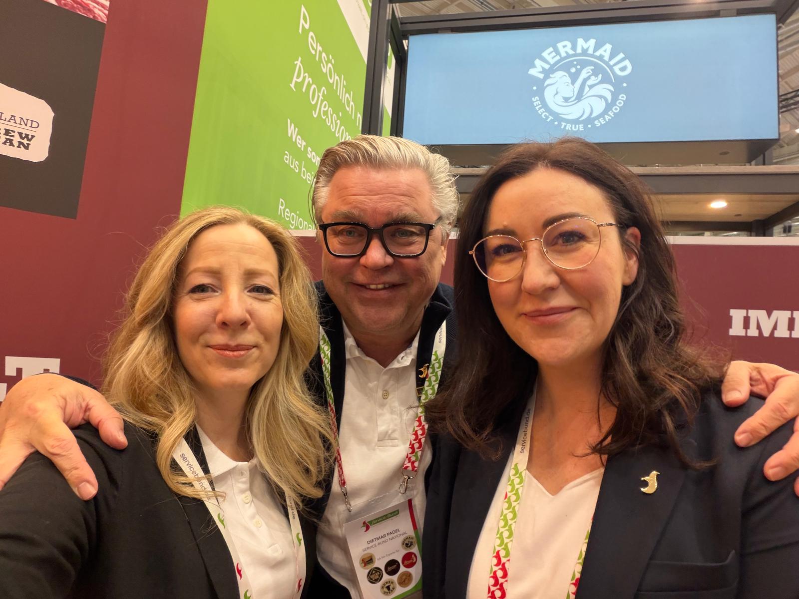 Eine Gruppe von Menschen lächelt für ein Foto, einige tragen Brillen.