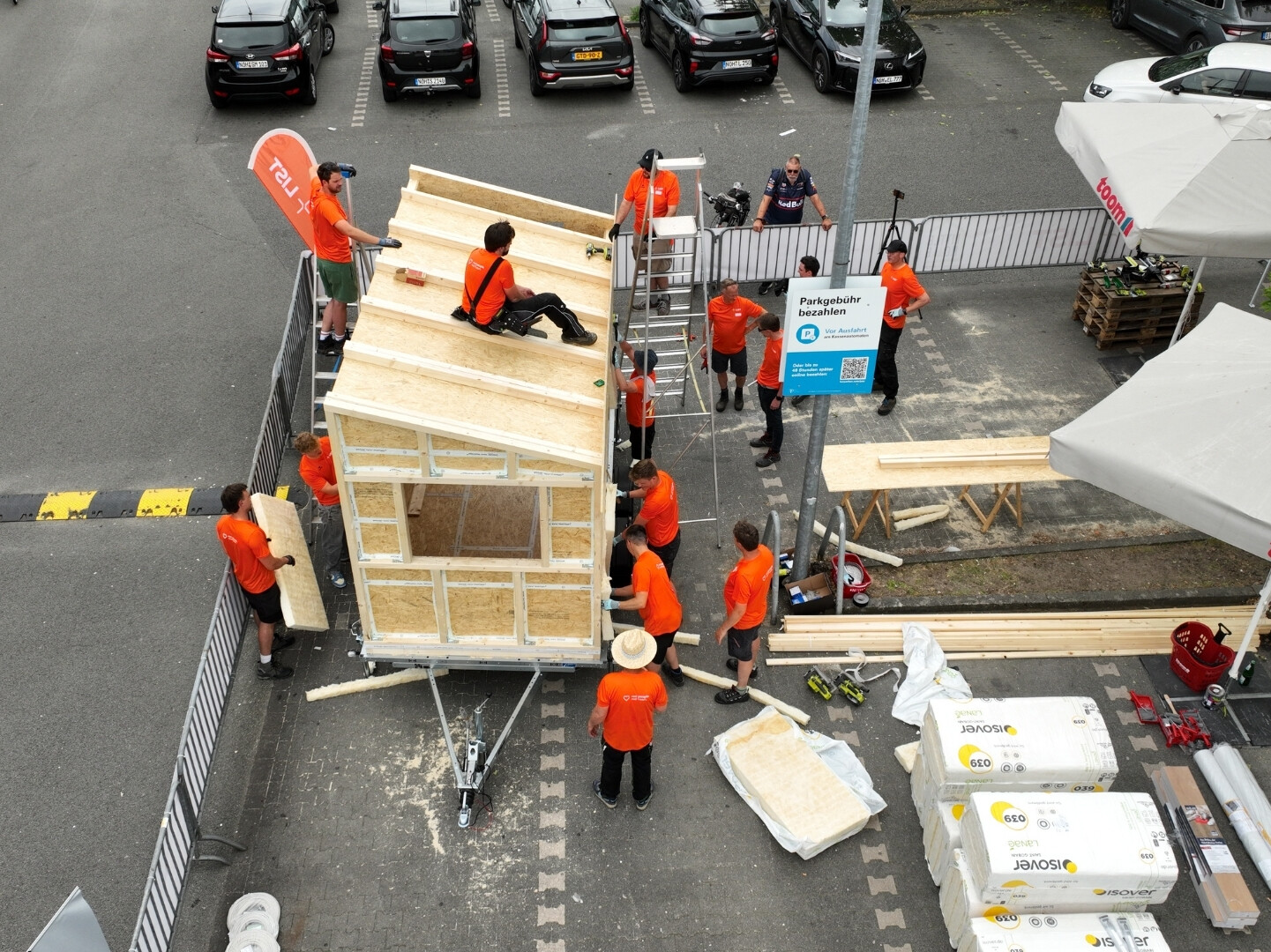 Eine Gruppe von Personen in orangefarbenen Hemden beim Bau eines Hauses.